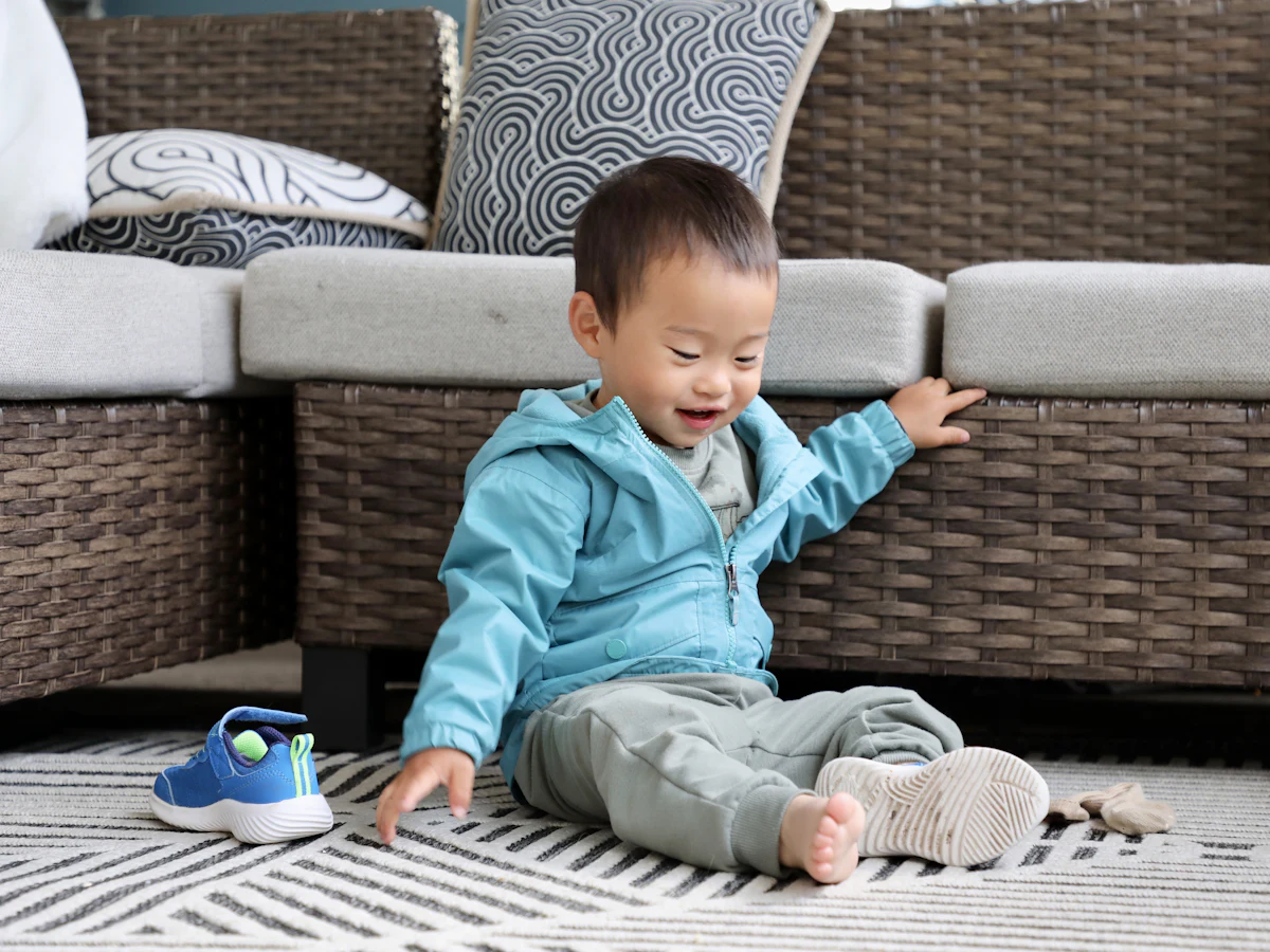 A smiling toddler sitting on a living room rug